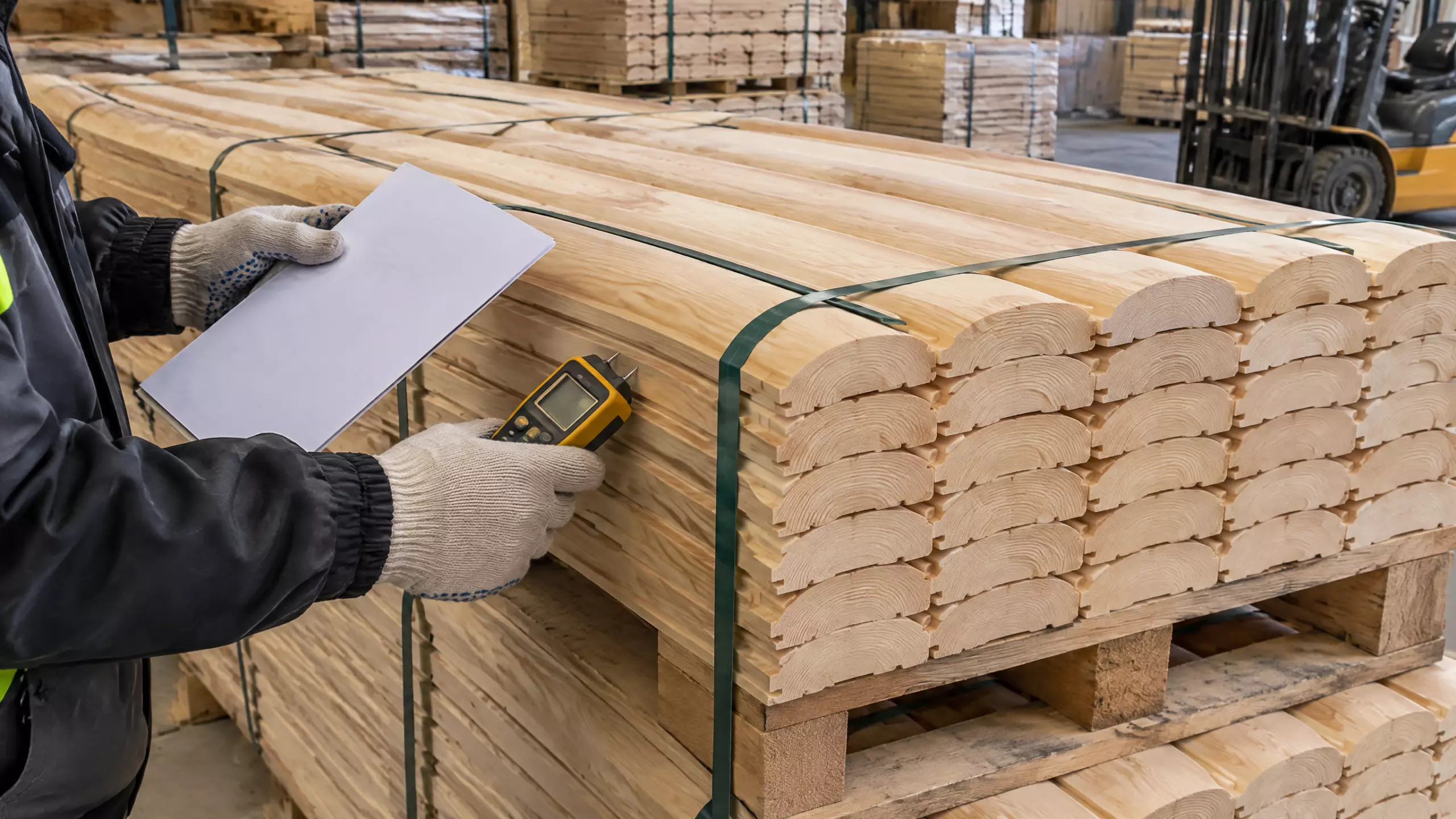 Рабочий проверяет влажность деревянного блок-хауса с помощью прибора и документации